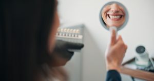 woman smiling into hand mirror